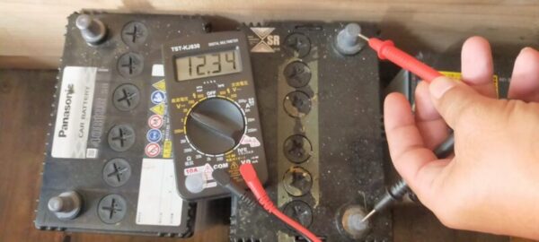 テスターを使ってバッテリー電圧計測中「12.34V」
